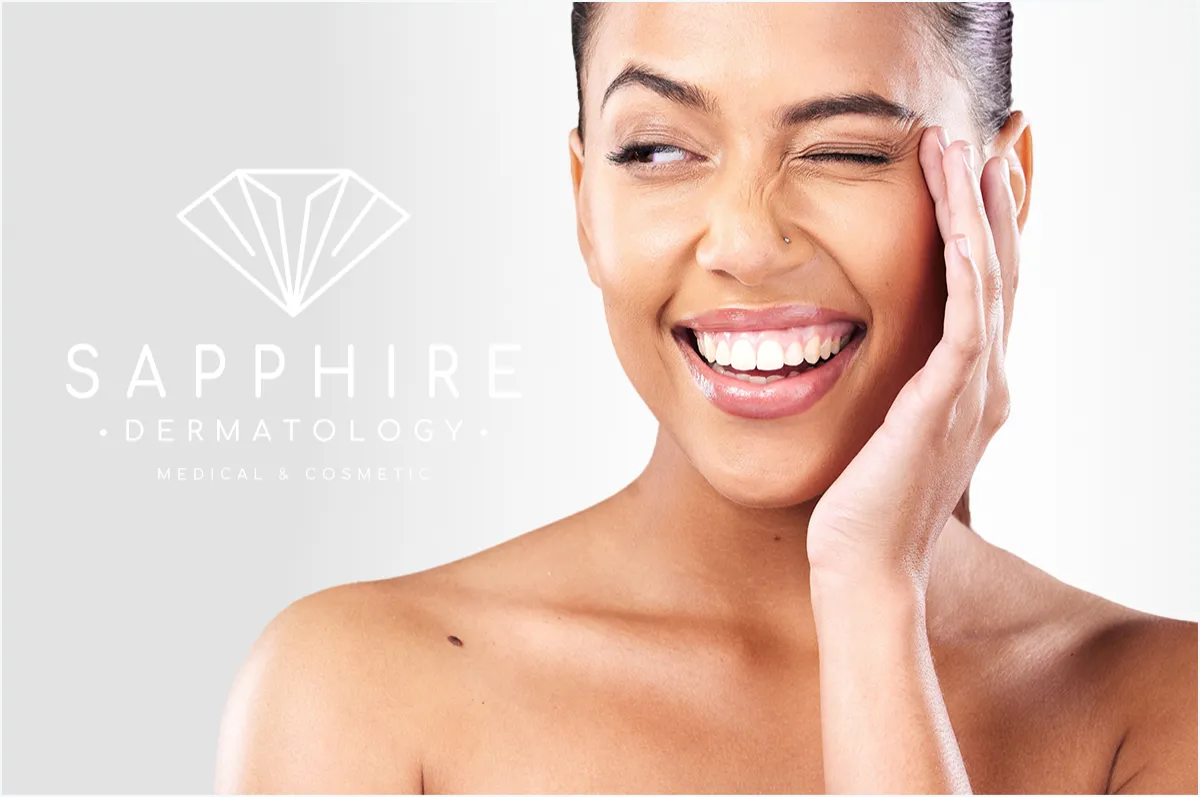 Smiling woman with clear skin winking next to Sapphire Dermatology logo