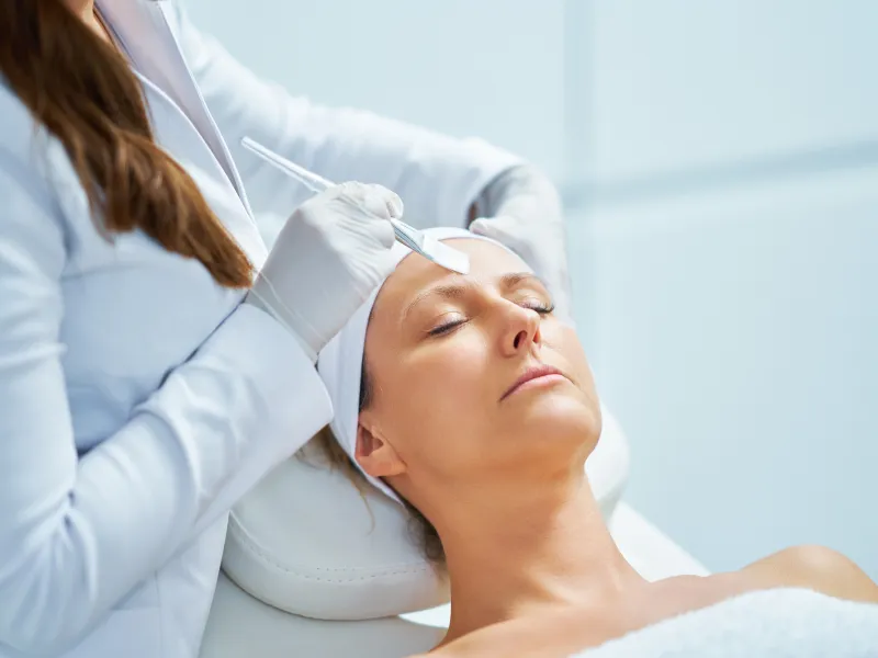 Woman receiving a facial treatment with a cosmetic tool at a dermatology clinic