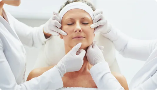Woman receiving a detailed facial examination by multiple dermatologists at a clinic